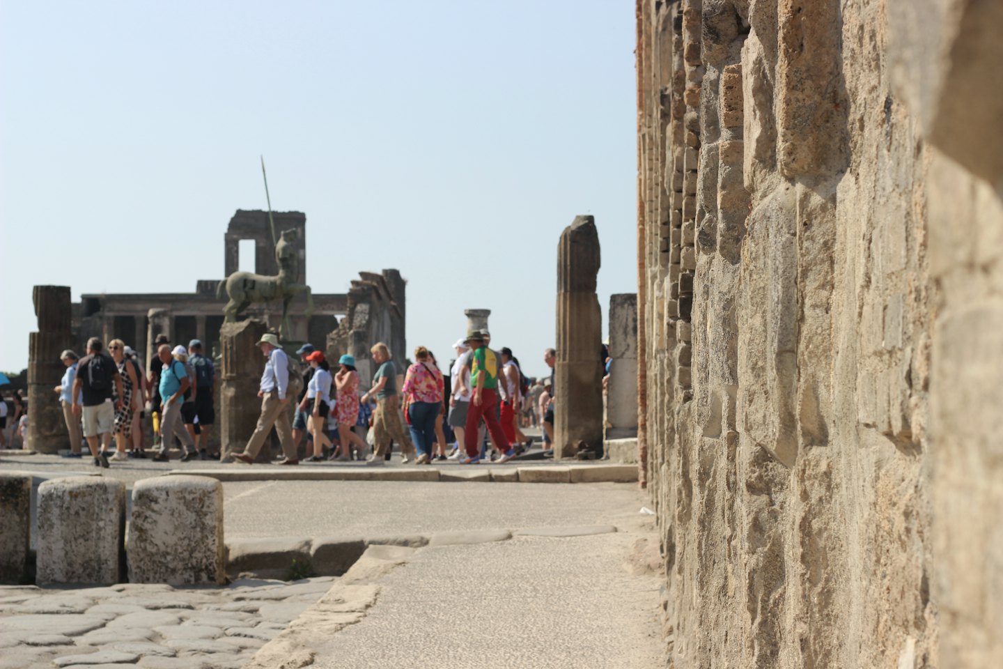 Tourists explore ancient ruins on a cobblestone path.