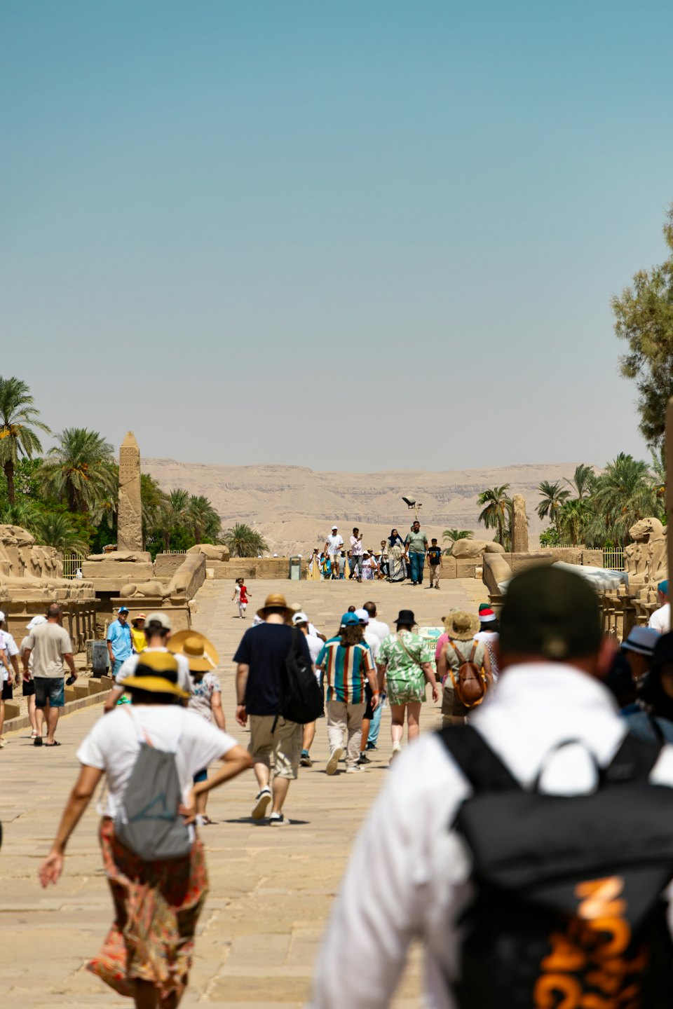 Tourists walk along a stone path at an archaeological site.